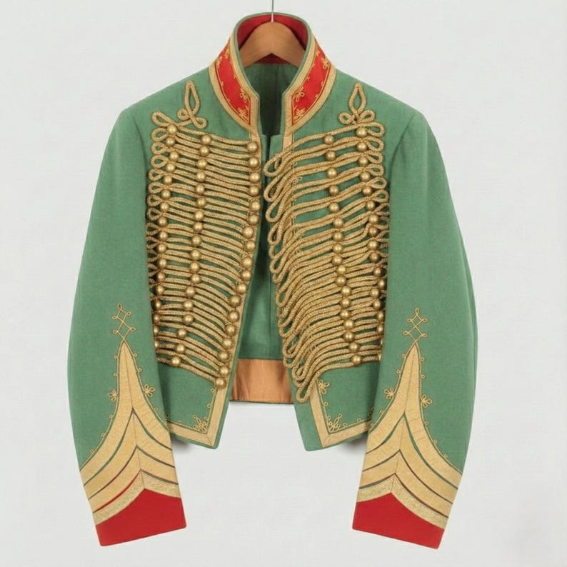 May include: A green military-style jacket with gold rope detailing and gold button accents. The jacket has red trim on the collar and cuffs. The jacket is hanging on a wooden hanger.