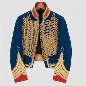 May include: A blue military-style jacket with gold rope detailing and gold button accents. The jacket has red trim on the collar and cuffs. The jacket is hanging on a wooden hanger.