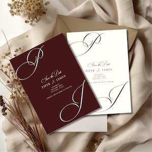 May include: Wedding invitation cards in burgundy and white, featuring elegant script. The text reads "Save the Date" with names and event details. The cards are displayed on a neutral background with dried flowers.