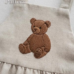 May include: A beige apron featuring an embroidered brown teddy bear on the chest. The text 'PDF Pattern' is visible in the upper left corner, and 'lumellu.etsy.com' is printed in a black rectangular box at the bottom of the garment.