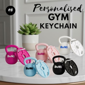 Pode incluir: Uma coleção de cinco porta-chaves com tema de ginásio nas cores rosa choque, rosa claro, branco, azul claro e preto. Cada porta-chaves apresenta uma miniatura de kettlebell e um disco de peso, ambos gravados com o texto BuMi.