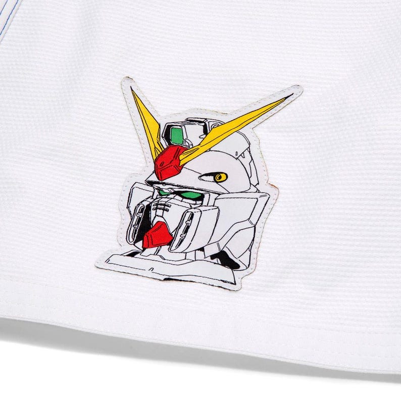 May include: White fabric with a robot head patch. The robot head design features yellow, red, green, and black details. The patch is sewn onto the fabric.
