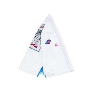 May include: White martial arts gi with a blue and red graphic on the shoulder. The gi features a blue and red logo on the sleeve and blue accents. The gi is folded, showing the inside and outside.