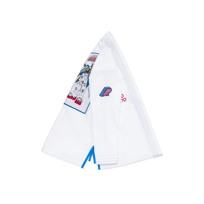 May include: White martial arts gi with a blue and red graphic on the shoulder. The gi features a blue and red logo on the sleeve and blue accents. The gi is folded, showing the inside and outside.