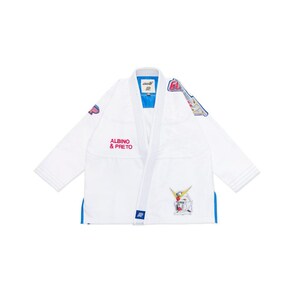 May include: White martial arts uniform with blue trim and accents. The uniform features the text "ALBINO & PRETO" in pink, along with colourful graphic patches. The uniform is designed for martial arts training and competition.