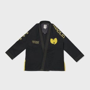 Puede incluir: Gi de artes marciales negro con detalles dorados. El gi presenta el logotipo y el texto de Wu-Tang Clan, incluyendo "PROTECT YA NECK" y "SHAOLIN". El gi tiene un ribete amarillo y está plano.