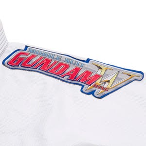 May include: A white garment with a blue trim and a patch featuring the text "MOBILE SUIT GUNDAM WING IV" in red, silver, and gold. The patch is outlined in blue and is likely an emblem or logo.