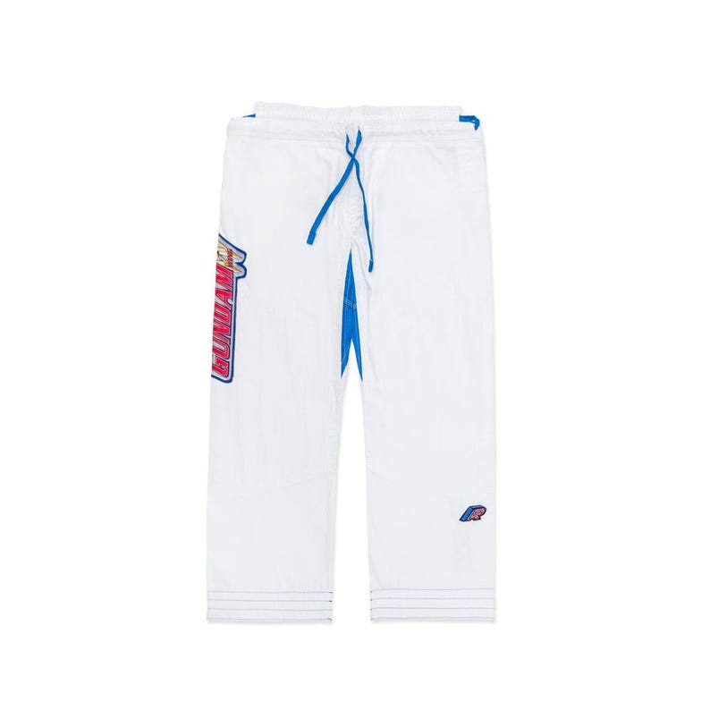 May include: White martial arts trousers with blue detailing and a drawstring. The trousers feature a large graphic on the left leg with the word "GUNDAM" in red, blue, and yellow. A small logo is on the right leg.