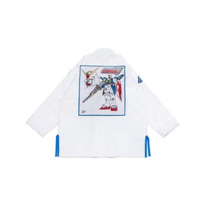 May include: White martial arts gi featuring a colourful robot graphic on the back. The robot is blue, red, and white, with the word "GUNDAM" above it. Blue accents are on the sleeves and sides.