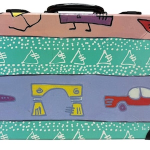 May include: A colorful suitcase with a black handle and corner protectors. The suitcase features a painted design with geometric shapes, a car, and an archway in shades of pink, teal, purple, and yellow.