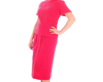 May include: A woman wearing a pink short-sleeved dress with a matching skirt. The dress has a round neckline and a textured fabric. She is wearing black heels.