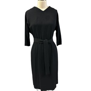 May include: A black knee-length dress with a V-neckline and a self-tie belt.