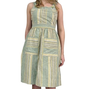 Puede incluir: Un vestido midi de rayas verdes y amarillas con cuello redondo y dos bolsillos grandes. El vestido tiene un corpiño ajustado y una falda fluida.