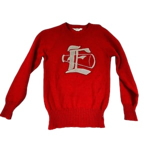 May include: A red sweater with a crew neck and long sleeves. The sweater features a large, silver-colored letter "E" with a megaphone design on the front. The cuffs and hem are ribbed.