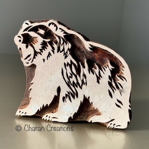 May include: A wooden block carving of a bear, with a white background and brown lines, used for printing designs on fabric.
