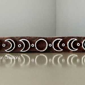 May include: A rectangular, dark brown wooden block with a repeating pattern of crescent moons and circles in white. The block is likely used for printing or stamping. The text "© Charan Creations" is visible in the lower left corner.