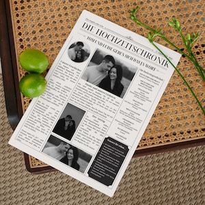 May include: A newspaper titled "DIE HOCHZEITSCHRONIK" with the headline "TOM UND LUISE GEBEN SICH DAS JA-WORT" rests on a wicker chair. The newspaper contains black and white photos and text. Two green limes and a sprig of greenery are also visible.