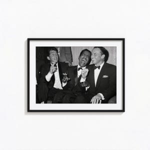 May include: A black and white framed photograph featuring three men in formal suits and bow ties, laughing together. The men are seated, with two holding cigarettes. The image is presented in a thin black frame with a white mat border.