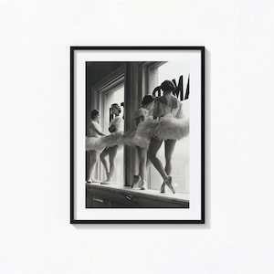 Könnte beinhalten: Ein schwarz-weiß gerahmter Wandkunstdruck, der vier Balletttänzer in Tutus an einem großen Fenster zeigt. Die Tänzer stehen in einer Reihe, tragen Spitzenschuhe und mehrlagige Röcke, wobei der Teiltext AMP auf der Fensterscheibe zu sehen ist.