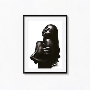 May include: A framed black and white photographic print featuring a portrait of a person with long dark hair, eyes closed, and arms crossed over their chest. The subject is captured in high contrast against a stark white background.