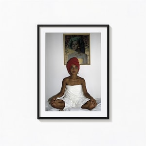 Puede incluir: Una impresión artística enmarcada que muestra a una persona con un turbante rojo y una toalla blanca envuelta alrededor del cuerpo, sentada en posición de meditación. Arriba cuelga un retrato enmarcado de una persona con turbante verde.