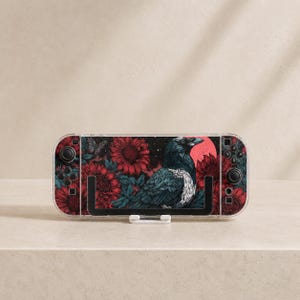 May include: A handheld gaming console featuring a decorative skin with a black raven, dark red sunflowers, and a red moon against a dark background. The device has black joysticks, directional buttons, and action buttons on both sides of the screen.