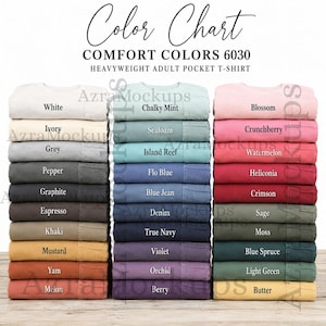 Op de afbeelding: Een kleurenkaart voor Comfort Colors 6030 zware t-shirts met zak voor volwassenen, met drie verticale stapels gevouwen t-shirts in verschillende tinten. Elk t-shirt is gelabeld met de kleurnaam, waaronder White, Ivory, Grey, Pepper, Graphite, Espresso, Khaki, Mustard, Yam, Melon, Chalky Mint, Seafoam, Island Reef, Flo Blue, Blue Jean, Denim, True Navy, Violet, Orchid, Berry, Blossom, Crunchberry, Watermelon, Heliconia, Crimson, Sage, Moss, Blue Spruce, Light Green en Butter.