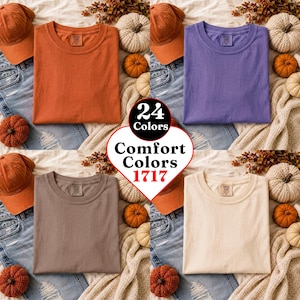 May include: A collage of four Comfort Colors 1717 t-shirts in orange, purple, brown, and cream. Each shirt is displayed with a matching baseball cap, blue jeans, and small pumpkins. The central heart-shaped graphic displays the text 24 Colors Comfort Colors 1717.