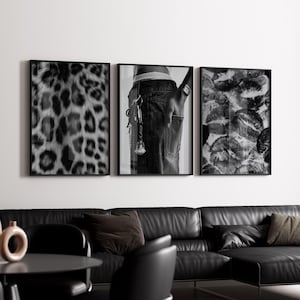 Puede incluir: Un tríptico de impresiones en blanco y negro enmarcadas. Una presenta un patrón de estampado de leopardo, otra muestra el bolsillo trasero de una persona con llaves y la tercera muestra múltiples huellas de labios. Las impresiones se exhiben sobre un sofá de cuero negro.