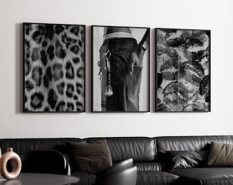 May include: A triptych of framed black and white prints. One features a leopard print pattern, another shows a person's back pocket with keys, and the third displays multiple lip imprints. The prints are displayed above a black leather sofa.