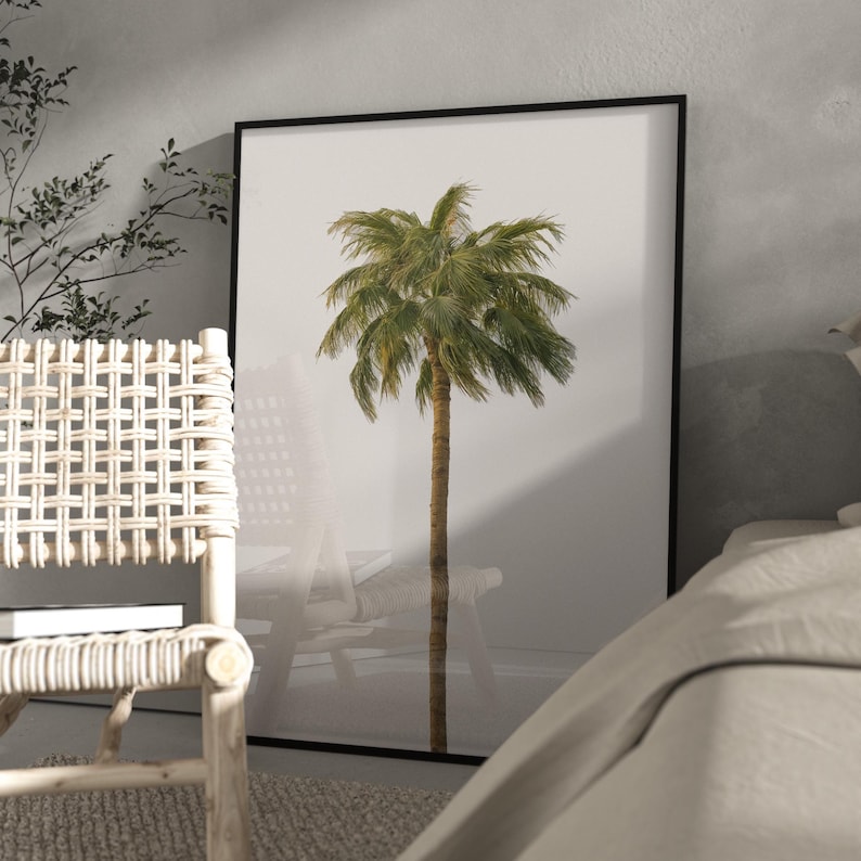 May include: A framed print depicting a palm tree illustration. The tree has a brown trunk and green fronds, set against a white backdrop. The artwork is enclosed in a black frame, suitable for home decor, with a minimalist aesthetic.
