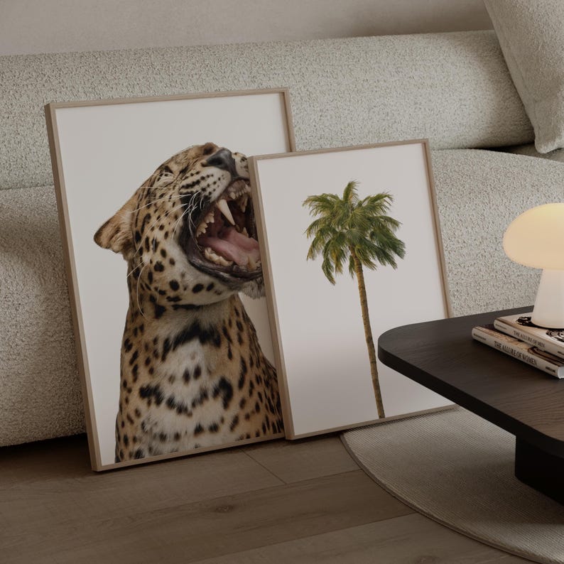 May include: Two framed art prints. One depicts a roaring leopard with visible teeth and spots. The other shows a palm tree against a white background. Both are in light wood frames, suitable for home decor.
