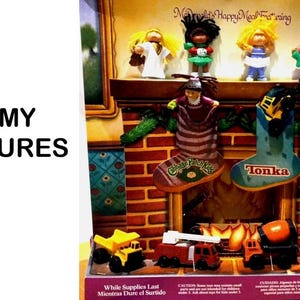 May include: A McDonald's Happy Meal toy set featuring four Cabbage Patch Kids dolls on a fireplace mantel, two stockings labelled Cabbage Patch Kids and Tonka, and four small construction vehicles including a yellow dump truck and red fire truck.