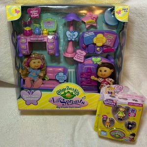 May include: A Cabbage Patch Kids Lil' Sprouts Best Friends Sleepover playset. The set includes two dolls, furniture, and accessories. The packaging is yellow and features the Lil' Sprouts logo and the text "Big Dreams Start Small!"