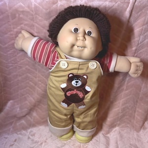 Vintage Cabbage Patch Kid Jungenpuppe • Variante mit zwei Zähnen • Seltenes HTF #517 Goldener Teddybär-Latzhosen-Outfit • Braunes, flauschiges Garnhaar, braune Augen