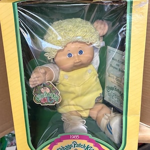 Bring home a piece of 1980s nostalgia with this pristine, "New in Box" 1985 Cabbage Patch Kid!