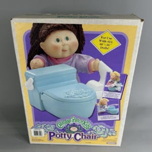 May include: A Cabbage Patch Kids Potty Chair toy box featuring a light blue plastic toilet with a white flush handle. The packaging displays a doll with brown yarn hair and text stating For Use With ALL 10-16 inch Dolls and Potty Chair.