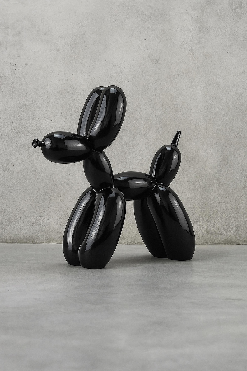 Op de afbeelding: Een glanzende zwarte ballonhond sculptuur. De sculptuur is een gestileerde weergave van een hond, gemaakt van een reeks opgeblazen ballonvormen. De hond staat op een grijze ondergrond tegen een neutrale achtergrond.