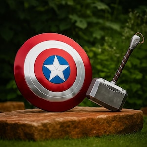 May include: A Captain America shield in red, white, and blue, with a silver rim and a white star, beside Thor's hammer. The hammer has a silver head and a brown handle. The items are on a stone surface.