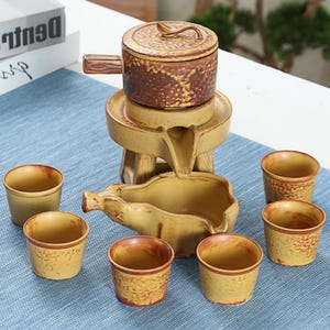 Peut inclure: Service à thé en céramique avec une finition marron et jaune. L'ensemble comprend une théière avec anse et couvercle, un plateau de service et six petites tasses. Le service à thé est de style rustique.