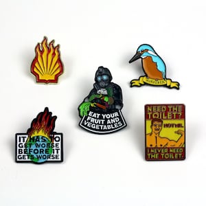 Może przedstawiać: Zestaw dziesięciu emaliowanych pinów z różnymi wzorami, w tym płomieniem, osobą w masce przeciwgazowej, zimorodkiem i muskularnym mężczyzną. Piny mają różne kolory, w tym czerwony, żółty, niebieski, zielony i czarny.