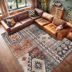 May include: A large rectangular area rug featuring a multi-colored geometric pattern in shades of burnt orange, cream, navy blue, and gray. The design includes repeating diamond shapes, intricate borders, and tribal-inspired motifs across the surface.