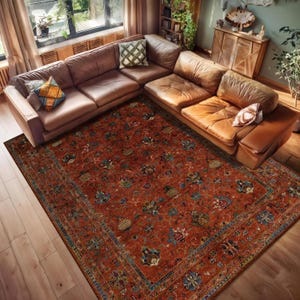 Pode incluir: Um tapete retangular grande com um intrincado padrão floral em tons de ferrugem, azul e verde. O tapete é colocado sobre um piso de madeira sob um sofá seccional de couro marrom, criando um espaço de convivência acolhedor.