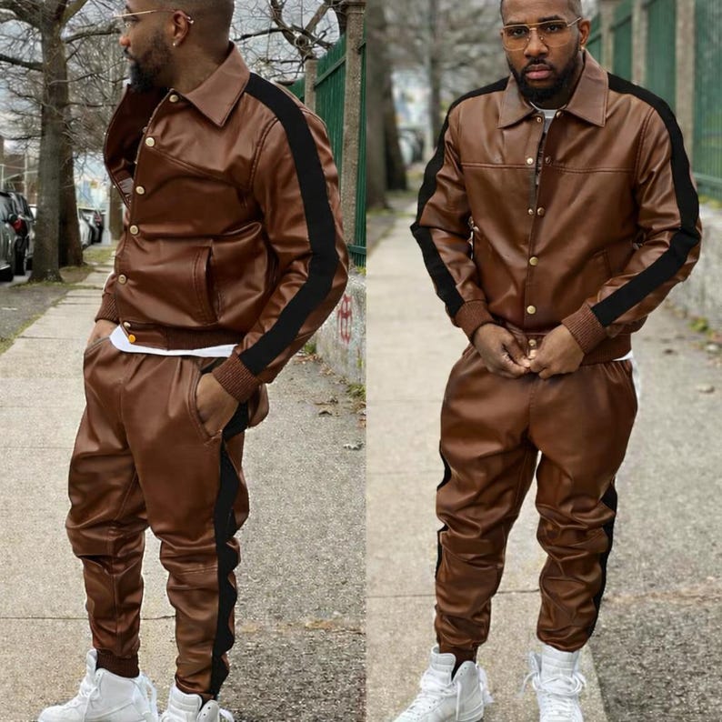 May include: A brown leather jacket and matching pants set with black stripes down the sleeves and legs. The jacket has a collared neckline and gold buttons. The outfit is paired with white sneakers. The ensemble is a stylish streetwear look.