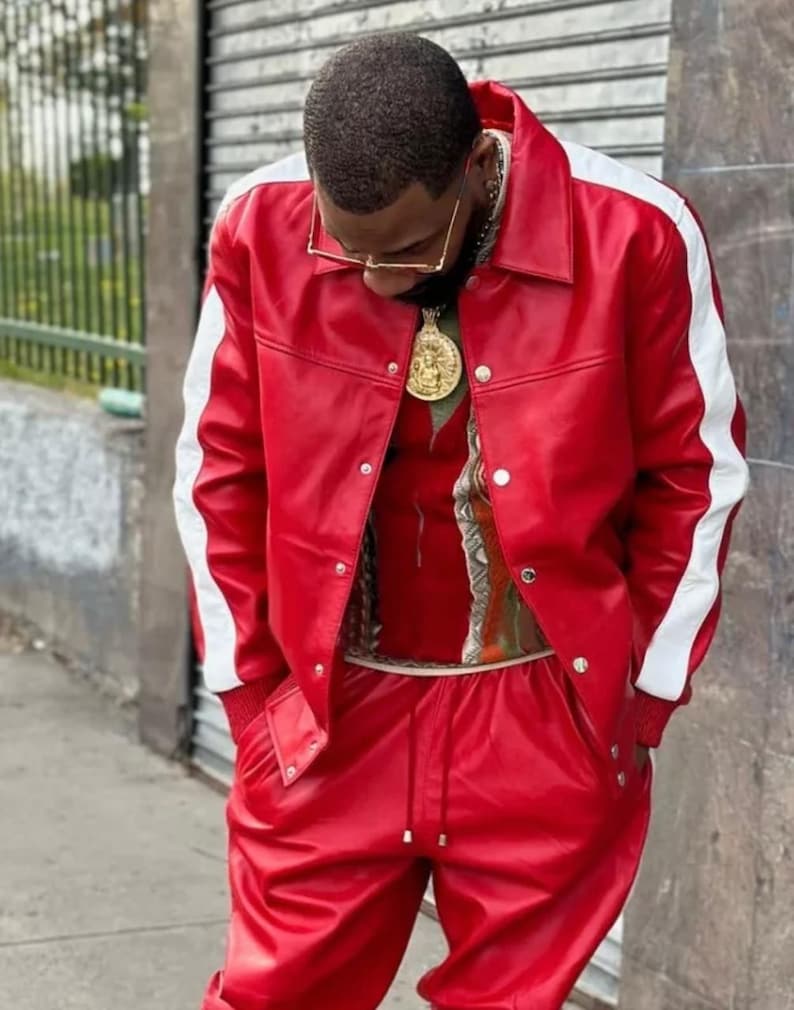 May include: A red leather jacket with white stripes down the sleeves and matching red pants. The jacket has a button-up front. A gold chain and pendant are visible.