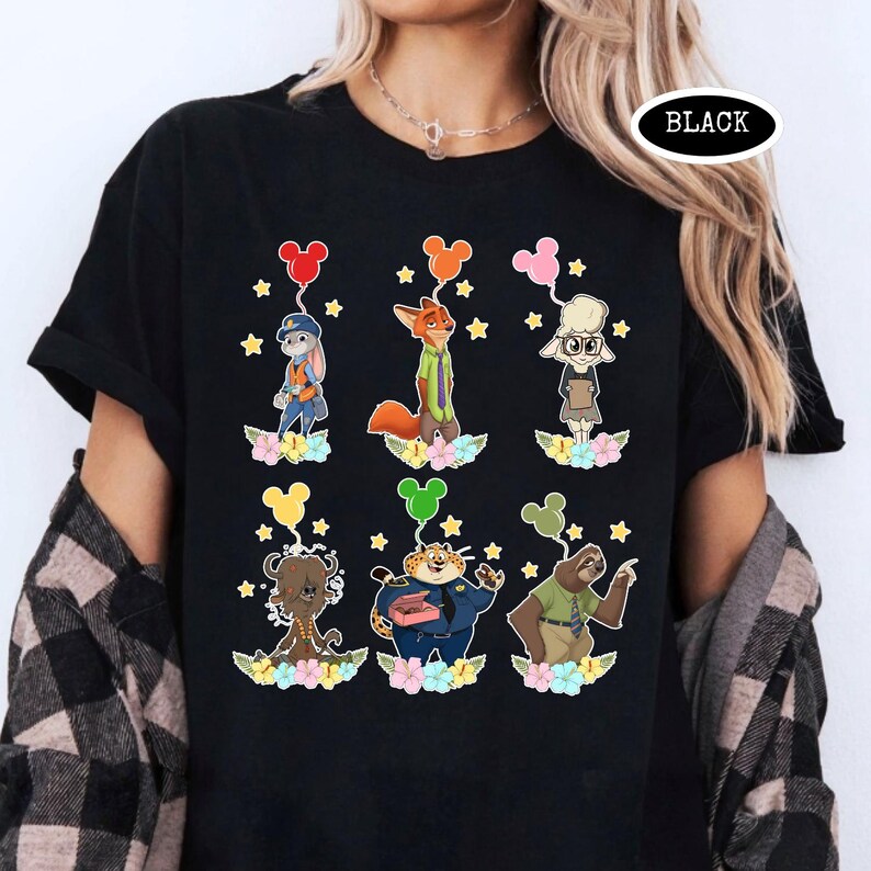 K&ouml;nnte beinhalten: Schwarzes T-Shirt mit Zeichentrickfiguren aus Zootopia, die jeweils einen Mickey-Mouse-f&ouml;rmigen Ballon halten. Die Figuren sind vor einem Hintergrund aus Blumen und Sternen platziert. Das Wort "BLACK" ist auf dem Shirt aufgedruckt.