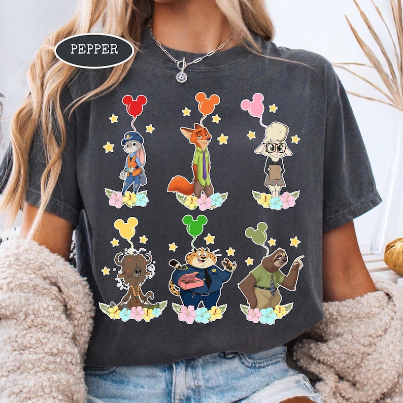 K&ouml;nnte beinhalten: Dunkelgraues T-Shirt mit Zeichentrickfiguren aus Zootopia, die jeweils einen Mickey Mouse-f&ouml;rmigen Ballon halten. Die Figuren sind vor einem Hintergrund aus Sternen und Blumen platziert. Das Wort "PEPPER" ist oben links aufgedruckt.