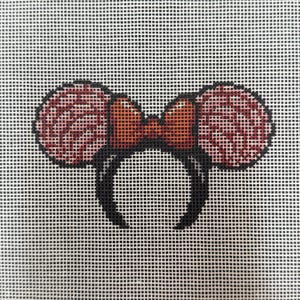May include: A hand-stitched canvas featuring a black headband with two round, pink ears and a red bow. The ears have a textured pattern, and the bow is a solid color. The background is a white grid.