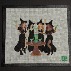 May include: Needlepoint canvas featuring four witches in black dresses and hats, gathered around a small brown table with green drinks. Each witch holds a green drink and a gold accessory. The background is a white grid.