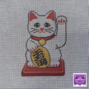 May include: A needlepoint design of a Maneki-neko, or Japanese lucky cat, with a raised paw. The cat is white with red accents on the ears, collar, and base. It holds a gold coin and sits on a red cushion. The background is a grid.